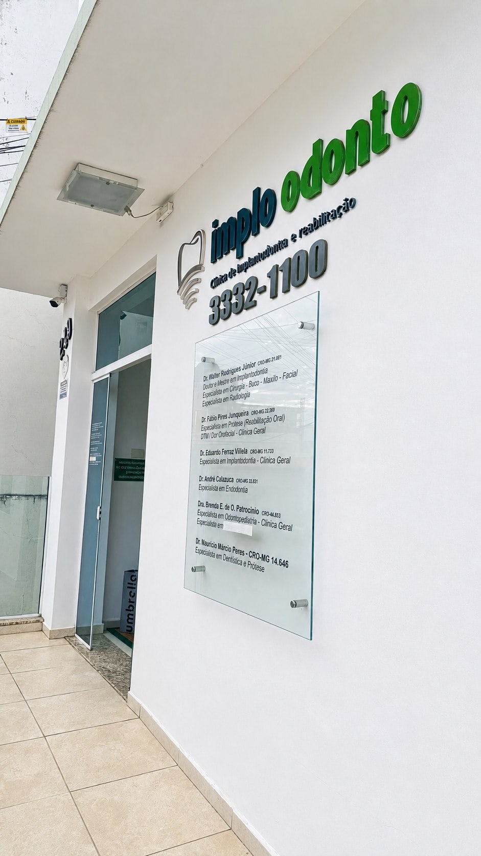 Entrada da Implo Odonto com letreiro e identificação dos profissionais